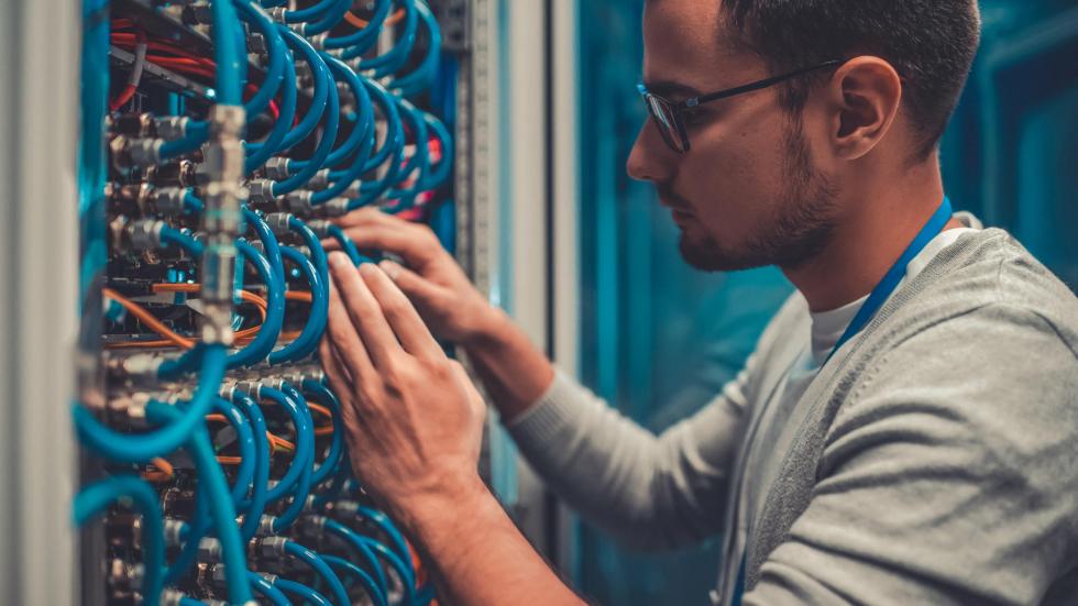 Ein junger Mann arbeitet in einem Serverraum an der Verkabelung